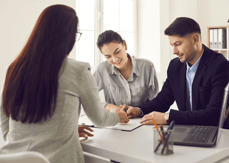 Business meeting with three people at desk.